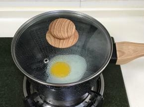 开小火，刷点食用油，往奶锅中磕入一个鸡蛋焖30秒，开盖后往鸡蛋四周撒点水滴，再次合盖，待蛋白凝固便可出锅。
