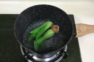 奶锅中倒入少许清水煮沸，加几滴食用油，下入油菜焯熟，蘑菇可多煮一会至熟。