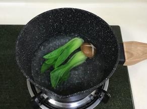 奶锅中倒入少许清水煮沸，加几滴食用油，下入油菜焯熟，蘑菇可多煮一会至熟。