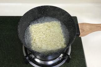 往奶锅中重新加清水煮沸，加入火鸡面，约煮5分钟，把汤汁倒掉些，留少许即可。