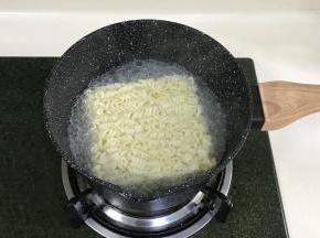 往奶锅中重新加清水煮沸，加入火鸡面，约煮5分钟，把汤汁倒掉些，留少许即可。
