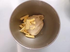 面团表面揉至表面光滑后加入软化的黄油，开低档揉至黄油完全融合于面团