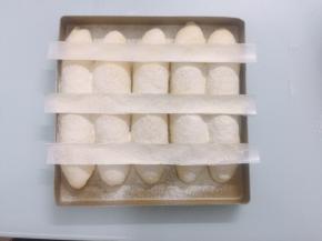 准备好一张油纸，剪成三张同样大小的长条，像图片这样，轻轻摆放在面包生胚的表面，均匀地筛上高筋面粉