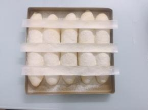 准备好一张油纸，剪成三张同样大小的长条，像图片这样，轻轻摆放在面包生胚的表面，均匀地筛上高筋面粉