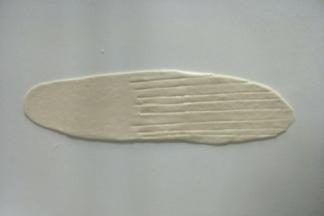 取一个小面团擀成牛舌状，其中一头用刀划几下，如图。