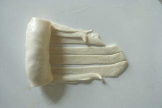 向另一头卷起，边卷边抻拉一下面团。