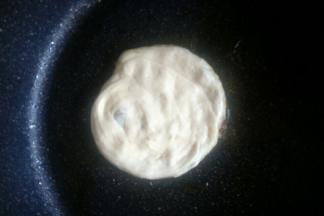 平底锅底刷一层玉米油，开中大火。把包入馅料的面团竖起按扁在平底锅中，在面团上也刷一层玉米油。