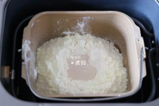 将冰水、蛋黄倒入面包机的面包桶中，盐、白砂糖对角放，再倒入面包粉和奶粉，粉中间挖个洞放入干酵母粉，启动面包机和面程序开始揉面；