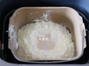 将冰水、蛋黄倒入面包机的面包桶中，盐、白砂糖对角放，再倒入面包粉和奶粉，粉中间挖个洞放入干酵母粉，启动面包机和面程序开始揉面；