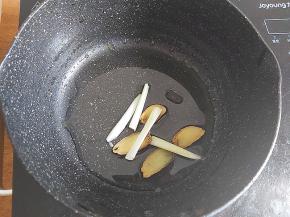 准备个小锅，倒入一大勺植物油，加入几片生姜、葱段，炸香。