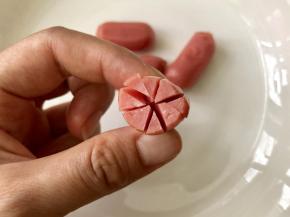 把小香肠的截面切“米”字花刀，切到一半，不要切断。