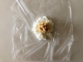 取一张保鲜膜，中间放入1/3碗米饭，铺平，中间再放一小片芝士片和肉松（芝士片留下一点做眼睛）。
