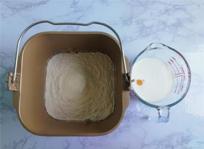 把高筋面粉，奶粉倒入面包桶中，接着分别倒入白砂糖，酵母，再倒入液体（鸡蛋和牛奶），最后倒入玉米油，启动面包机揉成面团。