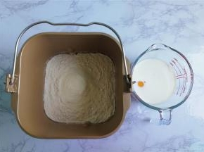 把高筋面粉，奶粉倒入面包桶中，接着分别倒入白砂糖，酵母，再倒入液体（鸡蛋和牛奶），最后倒入玉米油，启动面包机揉成面团。