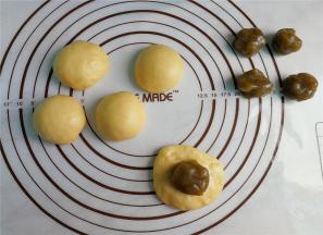 把每个面团揉搓排气，利用掌腹把面团按扁包入抹茶莲蓉馅，封口揉圆。