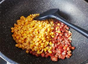 腊肠丁炒的微微焦黄，把玉米粒倒入一起翻炒片刻。