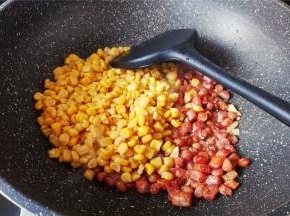 腊肠丁炒的微微焦黄，把玉米粒倒入一起翻炒片刻。