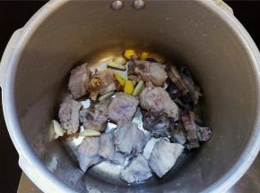 备一个高压锅，把排骨和墨鱼干放入，蒜瓣去皮切片，姜块洗净切片一起放入锅中。