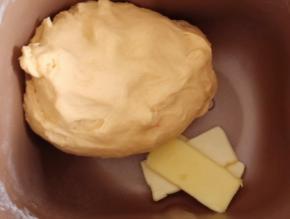 启动面包机揉面程序15分钟，面团揉光滑后，加入黄油。