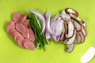 把蘑菇和青椒冲洗净沥干水分，用刀把蘑菇和香肠切片，青椒和洋葱切丝。