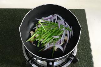 锅中倒8ml橄榄油，烧至微热，加入蘑菇片、洋葱丝、青椒丝和黑胡椒，中小火炒软。