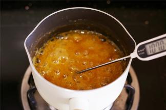 煮到将近沸腾后加入剩余的细砂糖和糖浆，继续用温度计检测温度，不时搅拌锅里，避免糊锅，锅里的果汁熬到107度后立刻熄火，震几下，把大气泡震掉。