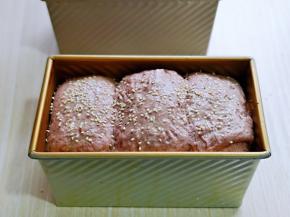 发酵至9分满。，保持面包胚的湿度，撒上白芝麻，椰蓉。