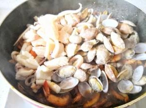 加入鱿鱼和花蛤翻炒均匀