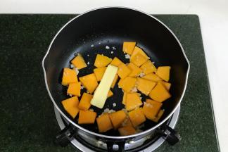 开火，锅中倒入食用油，加入蒜蓉爆香，接着加南瓜翻炒，加黄油。