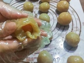 此刻，将蛋黄用咸馅包起来，每份莲蓉35克包裹一个蛋黄。我的这个蛋黄偏大了，15一个，小一点会更好包。