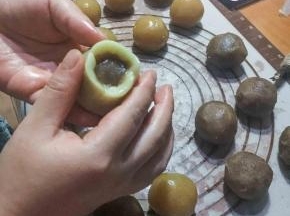 取出静置好的月饼皮，每个23克，用包包子的手法，把面皮一点一点往上推，排出空气，往上收口就可以了