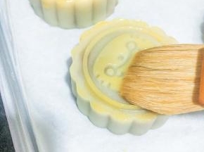 五分钟后取出刷上一层薄薄的蛋液！刷子每次沾起蛋液时在碗边来回得刮掉多余的蛋液，再轻轻刷至月饼纹路上。（切记不要重复刷多次，烤出来表面糊糊的就不好看了 。）