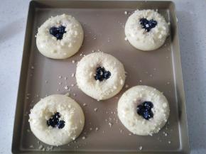 放进烤箱进行二次发酵，在二发好后如果蓝莓鼓起了就按压下去，面包胚上刷一层蛋液，表面撒适量酥粒（将黄油软化和其它材料混合，搓成小粒）。