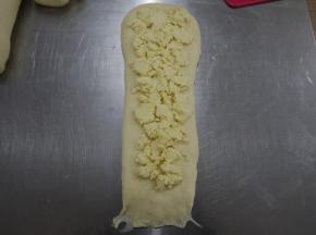 松弛好的面团再次擀成长条，放上椰蓉。椰蓉每个面团放50g。