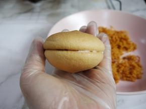 带上手套，拿一片蛋糕、在底部抹上一层沙拉酱，然后把另一片合上。