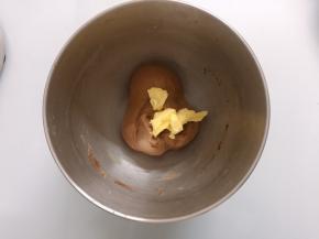 面团表面揉至表面光滑后加入软化的黄油，开低档揉至黄油完全融合于面团
