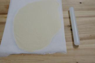 用擀面杖将面团擀成薄片，盖上油纸，放入冰箱冷藏30分钟