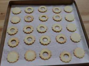将熬好的糖水倒入1/2个中间有圆孔的饼干胚内，记得留一半的圆孔饼干不要倒糖水。放至艾素糖水凉透变硬