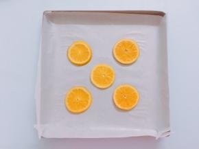 烤盘中铺好油纸，然后摆上5片橙片，不要摆的太靠边缘，会影响蛋糕卷