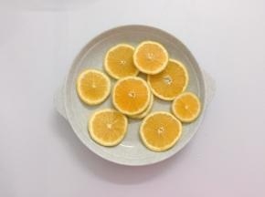 橙子先用盐搓洗后用水冲干净，清除部分蜡质表层，用刀切成薄片