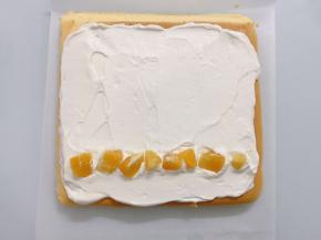 蛋糕卷表面薄薄抹一层奶油，摆入橙子丁