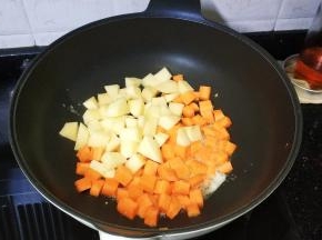倒入红萝卜、土豆丁翻炒1分钟