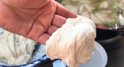 双手沾上水，取一小团面团，扒成厚面皮