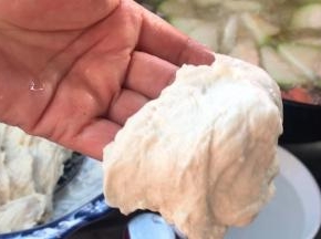 双手沾上水，取一小团面团，扒成厚面皮