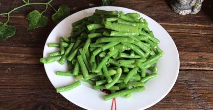 浸泡好的豆角，捞出切成小段，装入盘中