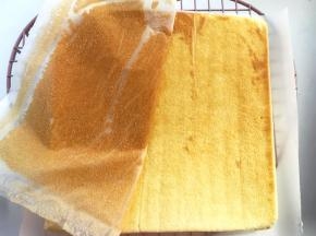 蛋糕降至手温时，将蛋糕翻转个面，底下记得铺上一张油纸，之后揭掉蛋糕上的油纸
