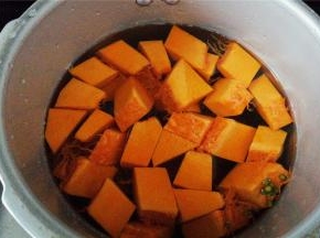 给南瓜去皮，去籽切小块，备个高压锅放入南瓜块，绿豆，再倒入适量的清水。