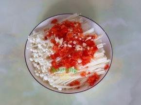 在金针菇的上面放盐、剁好的红辣椒、大蒜末，然后淋一点花橄榄油、麻油。不喜欢吃花椒麻辣味，可以不放麻油，个人觉得放麻油麻辣鲜香很过瘾的。