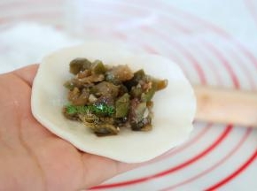 饺子皮拿在手上，放入适量的炒好的茄子馅，馅料要确保是冷却之后，热馅料千万不能放，饺子会裂开。