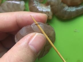 用牙签把虾线挑出来，挑虾线的技巧是在虾的第三节那里，找准虾线的位置，把牙签插进去一挑，轻轻一拉，虾线就出来了。